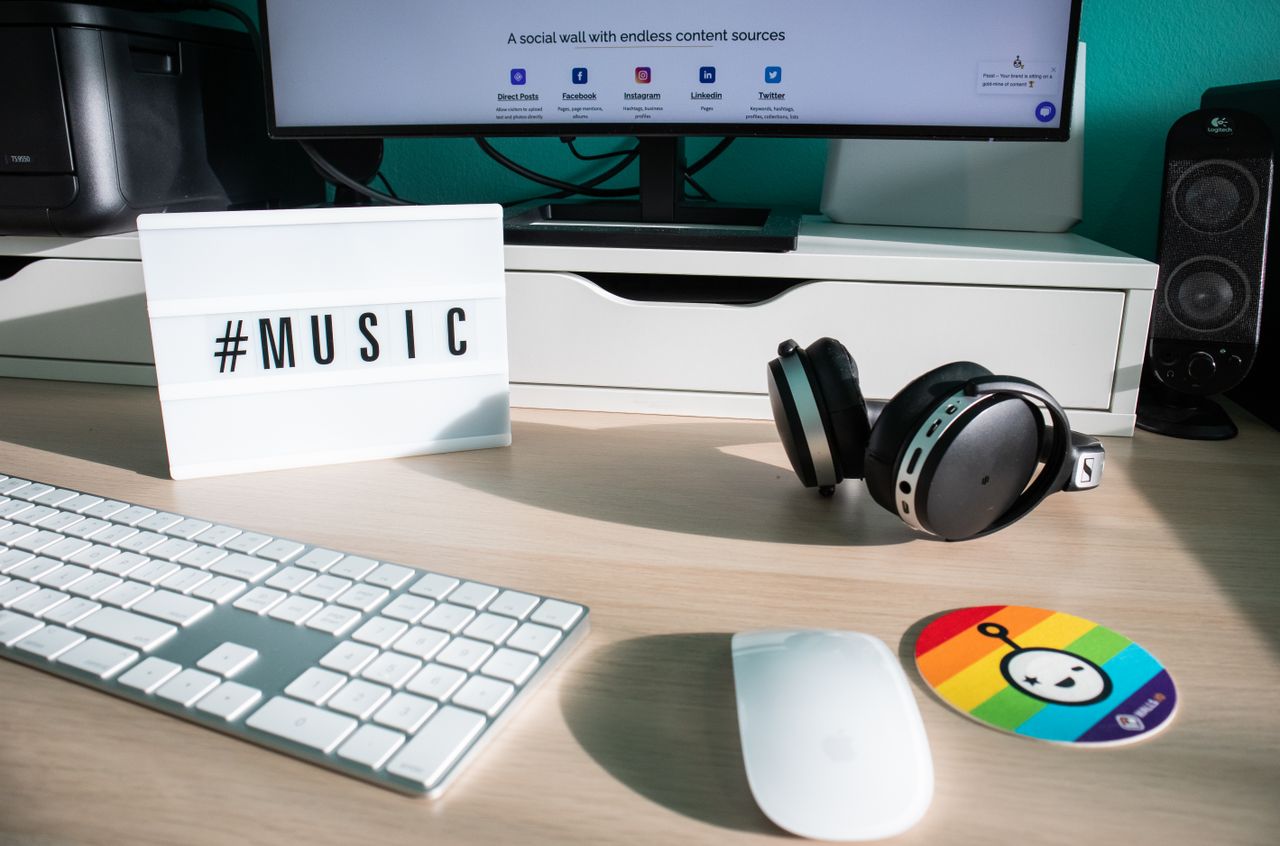 A creative desk setup featuring headphones, keyboard, mouse and a music-themed lightbox.