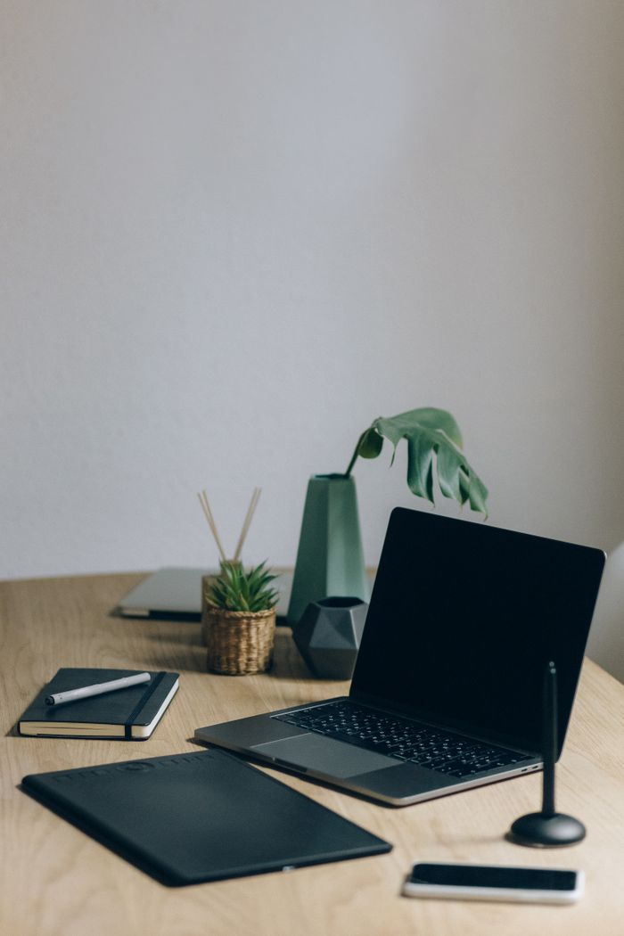 A minimalist home office setup featuring a laptop, notebook, and plant for a productive workspace.